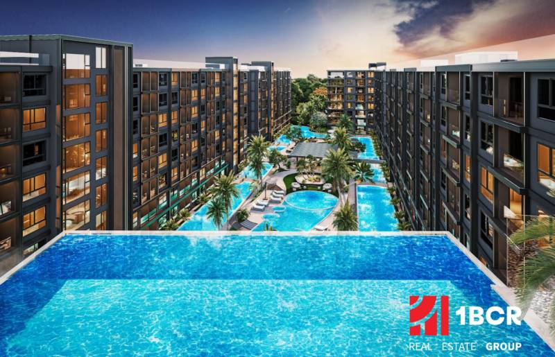 Apartment construction in Pattaya with large pools and palm trees between the buildings.