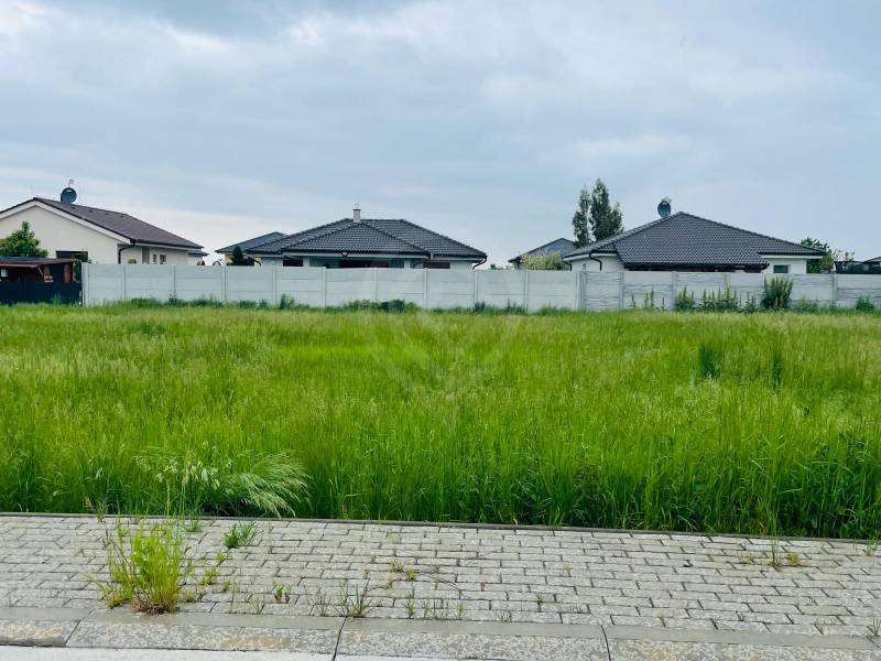 Land for residential use in the Hviezdoslavov area, Podháj, with green grass and neighboring houses.