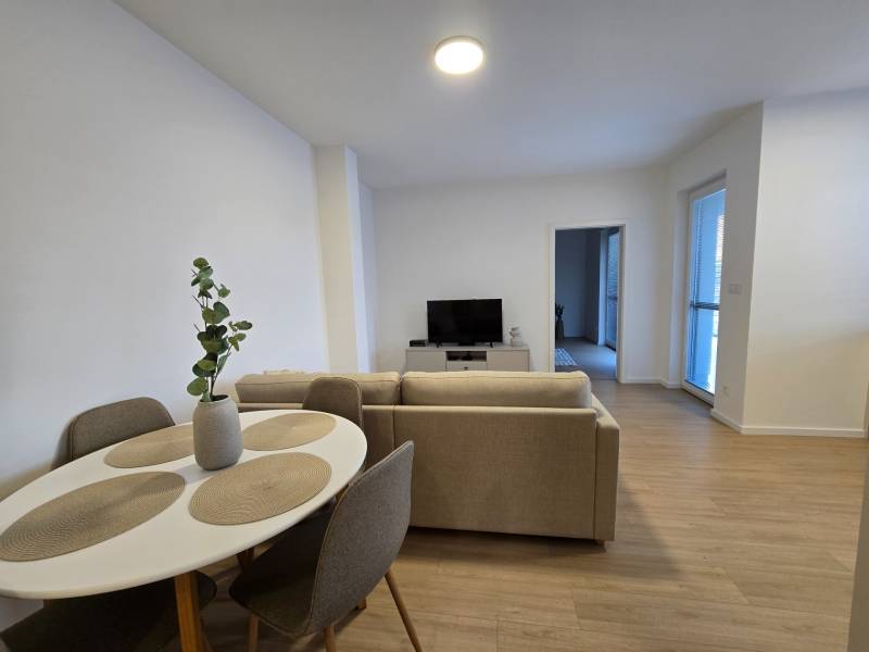 Living room in a three-room apartment with a wooden decor floor and a dining table.
