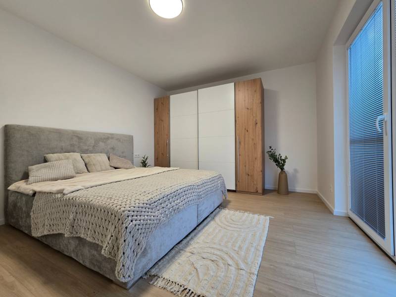 Bedroom in a 3-room apartment with a bed, wardrobe, and wooden decor flooring.