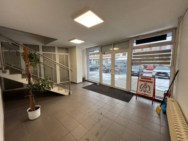 Interior of an office with tiling, a staircase, and glass doors.