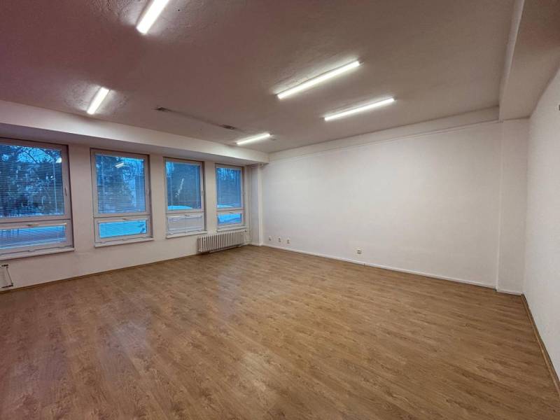 Offices with light walls and wooden decor flooring, large windows.