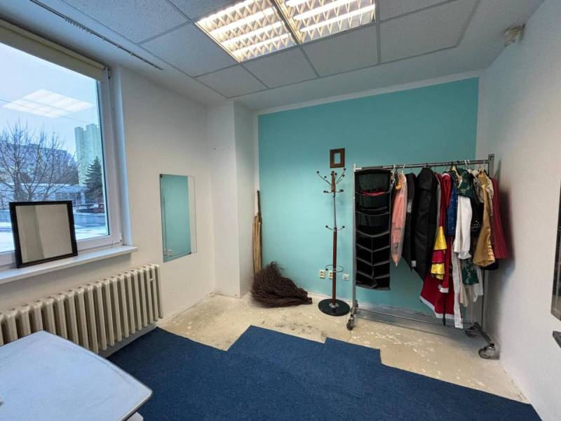 Room in offices with a coat rack, mirror, and blue wall.