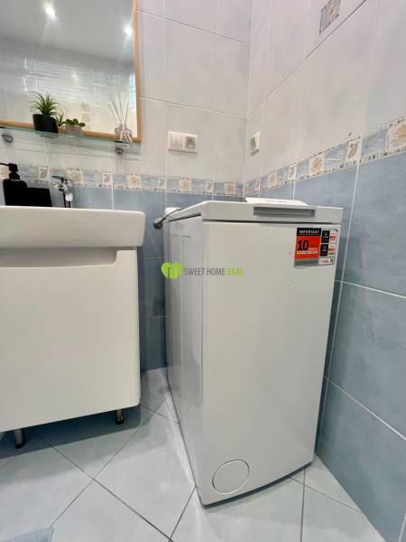 Bathroom with a washing machine and a sink in a 2-room apartment, blue tiles.