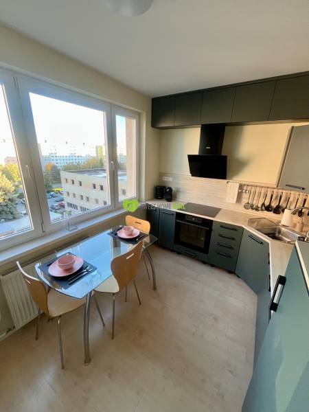 A kitchen in a 2-room apartment with a view, glass table, wooden floor decor.