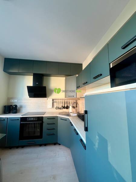 A kitchen in a 2-room apartment with blue cabinets and a wooden decor floor.