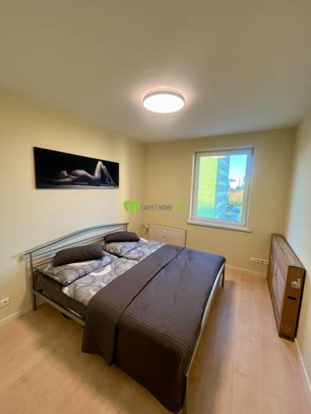 Cozy bedroom with wood-patterned flooring in a 2-room apartment, simple furnishings.
