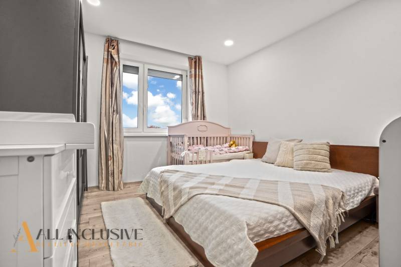 A bedroom in a 3-room apartment with a wooden decor floor and a baby crib.