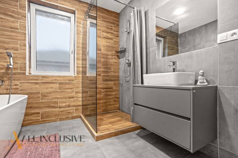 A bathroom with a wood-patterned floor in a 3-room apartment, includes a shower and a cabinet.