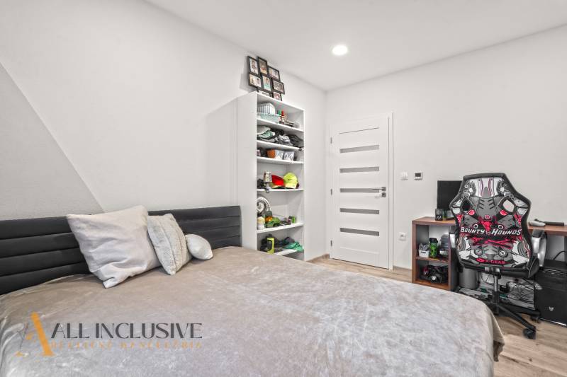 Bedroom in a 3-room apartment with a work corner and a shelf. Floor with wooden decor.