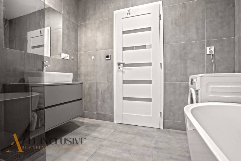 A bathroom in a 3-room apartment with white doors, a washing machine, and a sink.