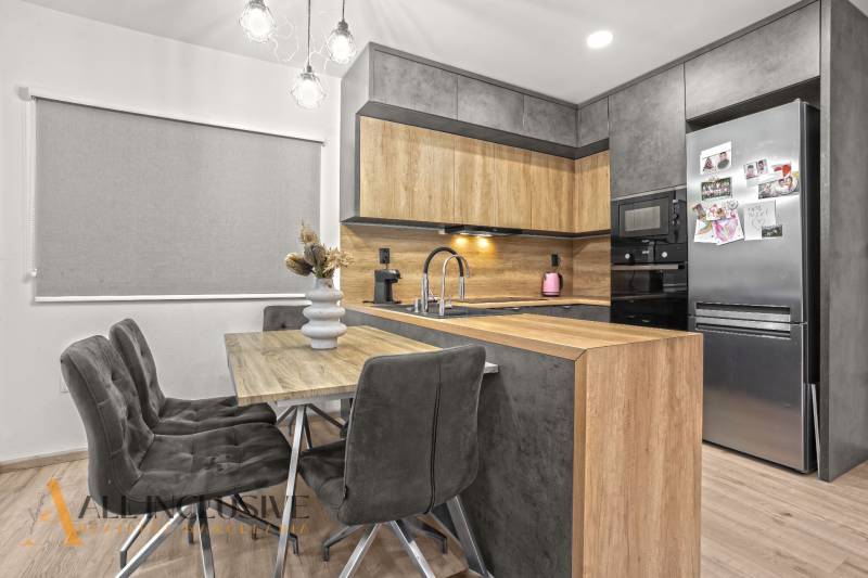 A kitchen corner with a wooden decor in a 3-room apartment with a stylish table and gray chairs.