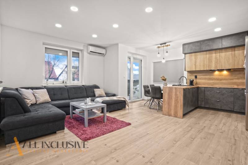 Living room with a kitchenette, gray sofa, wooden decor flooring, dining table.