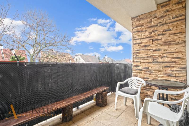 Balcony of a 3-room apartment in Vrakuňa with seating, brick cladding, and a view of the roofs.