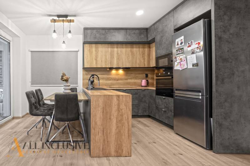 A kitchen in a 3-room apartment with a wooden decor floor, gray cabinets, and a dining table.