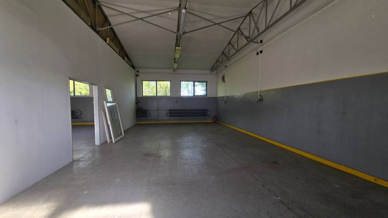 Interior of a warehouse with a metal structure, concrete floor, and windows.