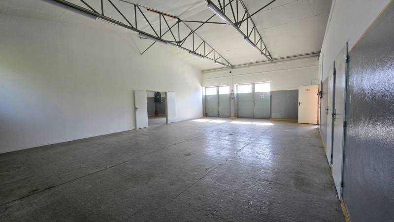 Spacious interior of warehouses and halls with concrete floors, white walls, and a metal ceiling.