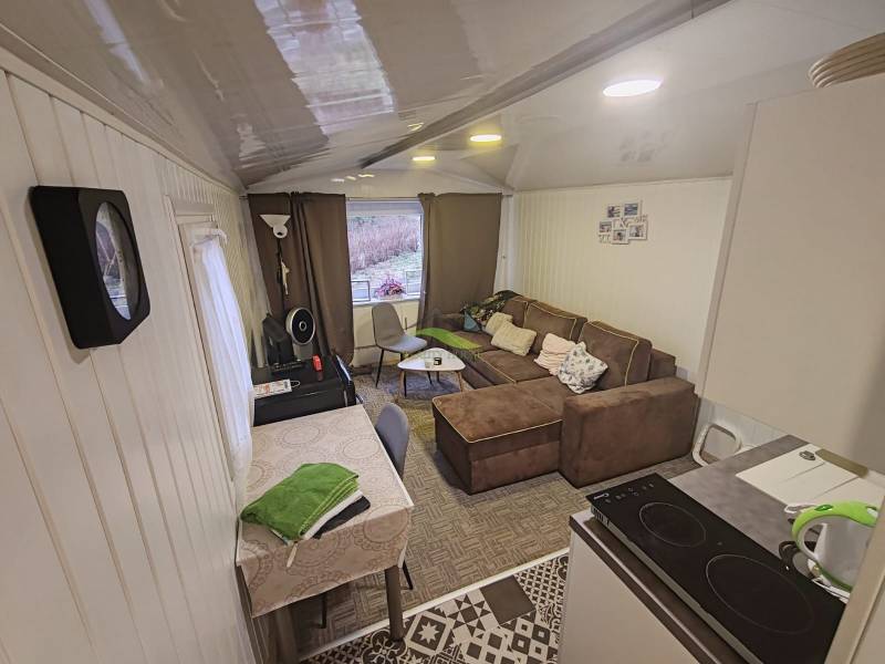 The interior of a cabin with a sofa, dining table, and equipped kitchen.