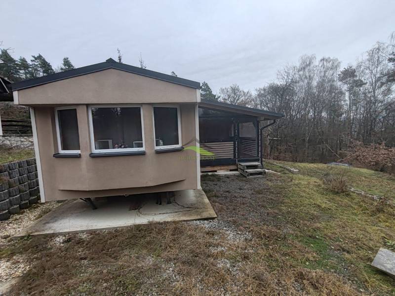 A cottage on Main Street in Nova Kelca surrounded by trees and gently sloping terrain.