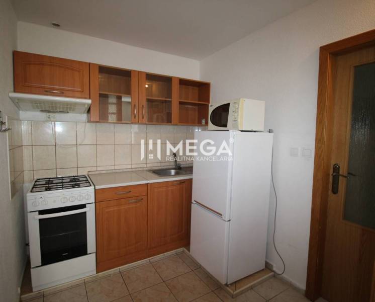 A kitchen in a 2-room apartment with a kitchen unit, refrigerator, and stove.