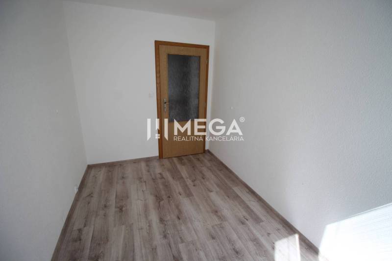 A room in a 2-room apartment with a wooden decor floor and doors.