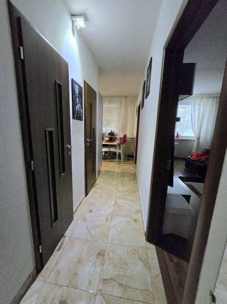 A hallway in a 3-room apartment with tiles and a view into the living room and kitchen.