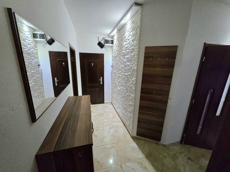 A hallway in a 3-room apartment with a decorative wall and a wardrobe, flooring with a wooden decor.