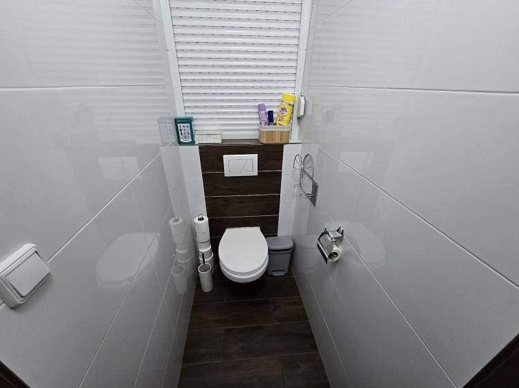 Bathroom with toilet and wooden decor flooring in a 3-room apartment.