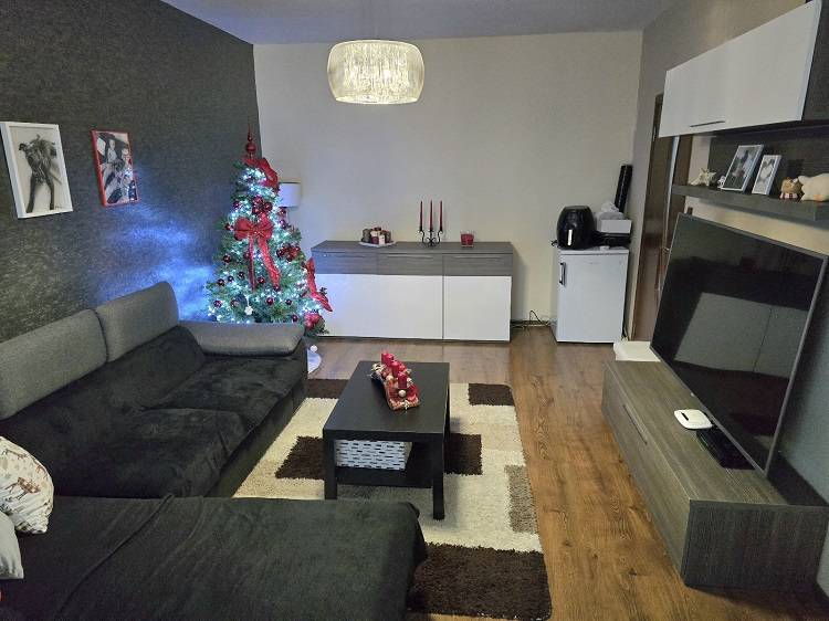 A living room decorated for Christmas in a three-room apartment with a wooden decor floor.