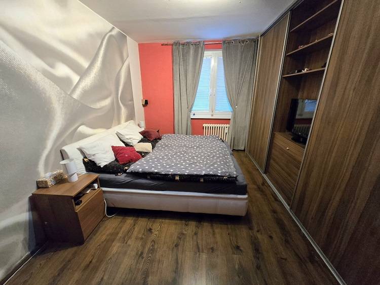 Bedroom with a bed, built-in wardrobes, and a wooden decor floor in a 3-room apartment.
