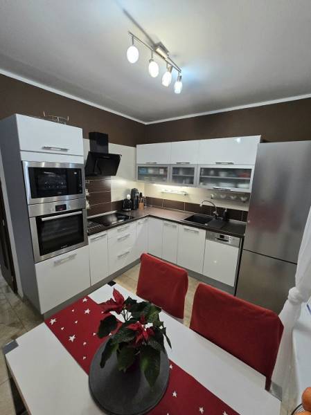 A kitchen in a 3-room apartment with white cabinets, stainless steel appliances, and decorations on the table.