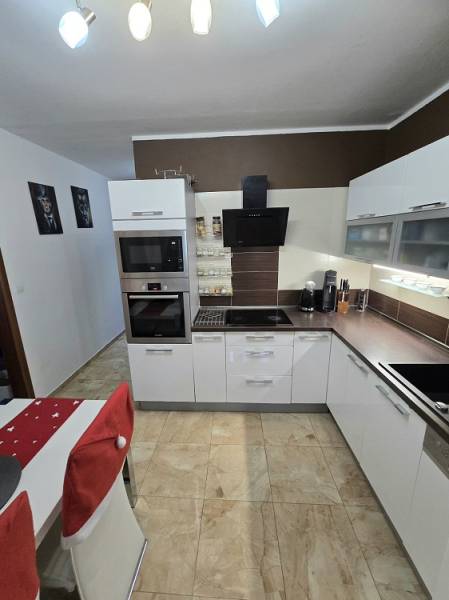 A kitchen in a 3-room apartment with light fixtures, white cabinets, and tiles.