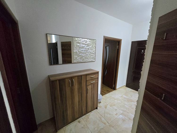 Hallway in a 3-room apartment with a tiled floor and a mirror above the cabinet.