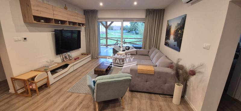 Living room in a family house with a wooden decor floor, corner sofa, and television.