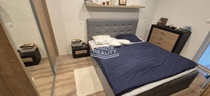 Bedroom with wood-patterned flooring, bed, and storage spaces in a family house.