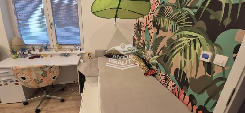 Children's room with a desk and colorful wallpaper with motifs in a family house.