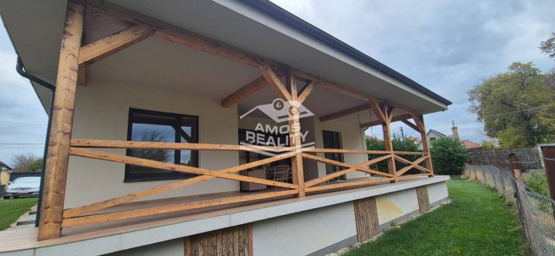 The family house in Studienka has a terrace with wooden railings and an adjacent lawn.