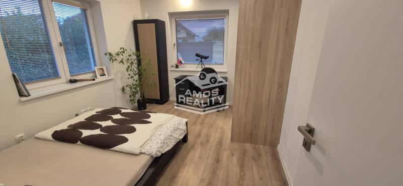 Bedroom with a bed, table, and wooden decor flooring in a family house.