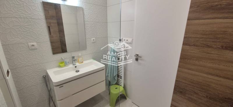 Bathroom in a family house with a sink, embossed tiles, mirror, and illuminated walls.