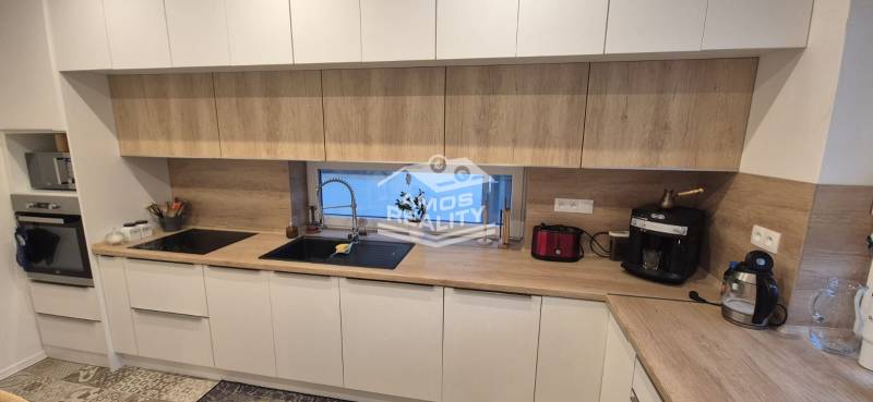 A kitchen in a family house with white cabinets and a wooden decor countertop.