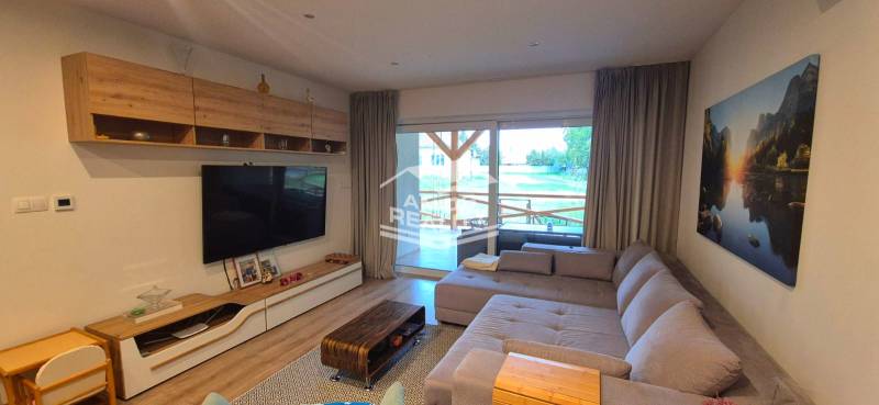 Living room of a family house with a sofa, a large television, and a wooden decor floor.