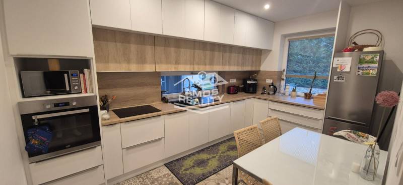 A kitchen in a family house with white cabinets, appliances, and a wooden decor floor.