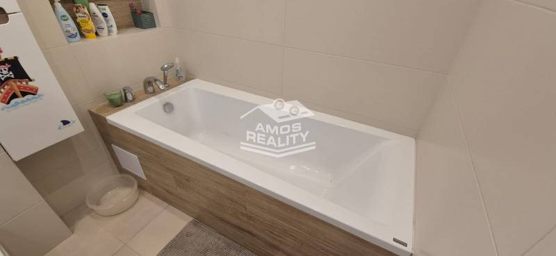 A bathroom with a bathtub decorated with wood decor in a family house.