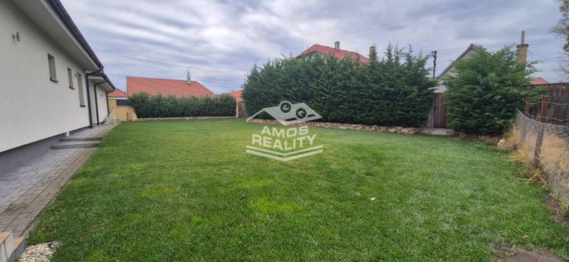 A family house in Studienka with a garden, manicured lawn, and tall hedge.