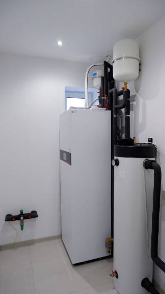 Bathroom equipment in a family house with boilers and pipes, light walls.