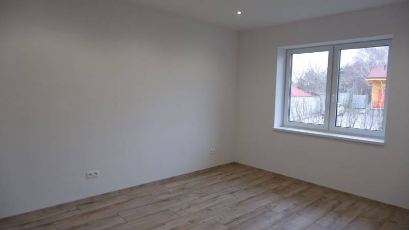 A room in a family house with white walls and a wooden decor floor.