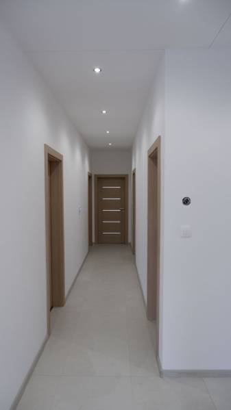 A hallway in a family house with white walls and wooden decor doors.