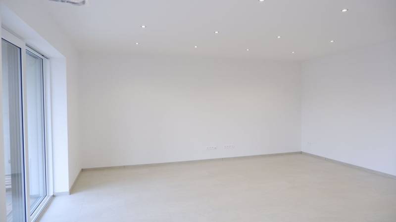 An empty room in a family house with white walls and a light floor.