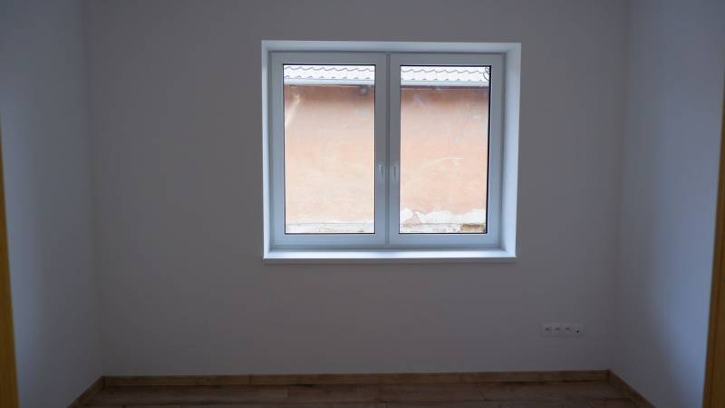 A room in a family house with a large window and a floor with a wooden decor.
