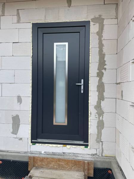 The entrance door of a family house in Radava, surrounded by brick masonry.